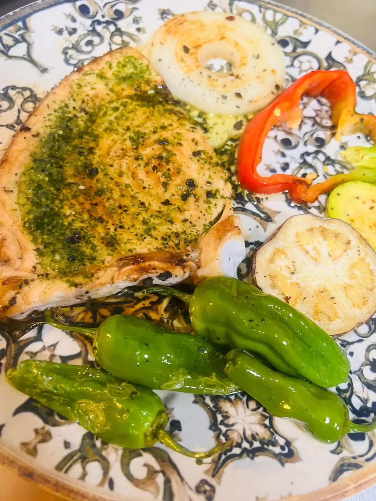 Rodaja de pescado a la plancha con salsa verde de ajo y perejil, con cebolla, pimiento rojo, calabacín y berenjena a la plancha y pimientos de Padrón.