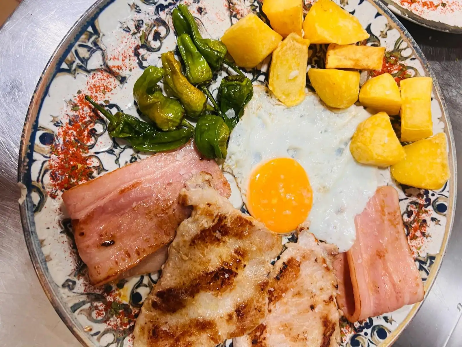 Plato con huevo frito, patatas, jamón york y lomo a la plancha, con pimientos de Padrón.