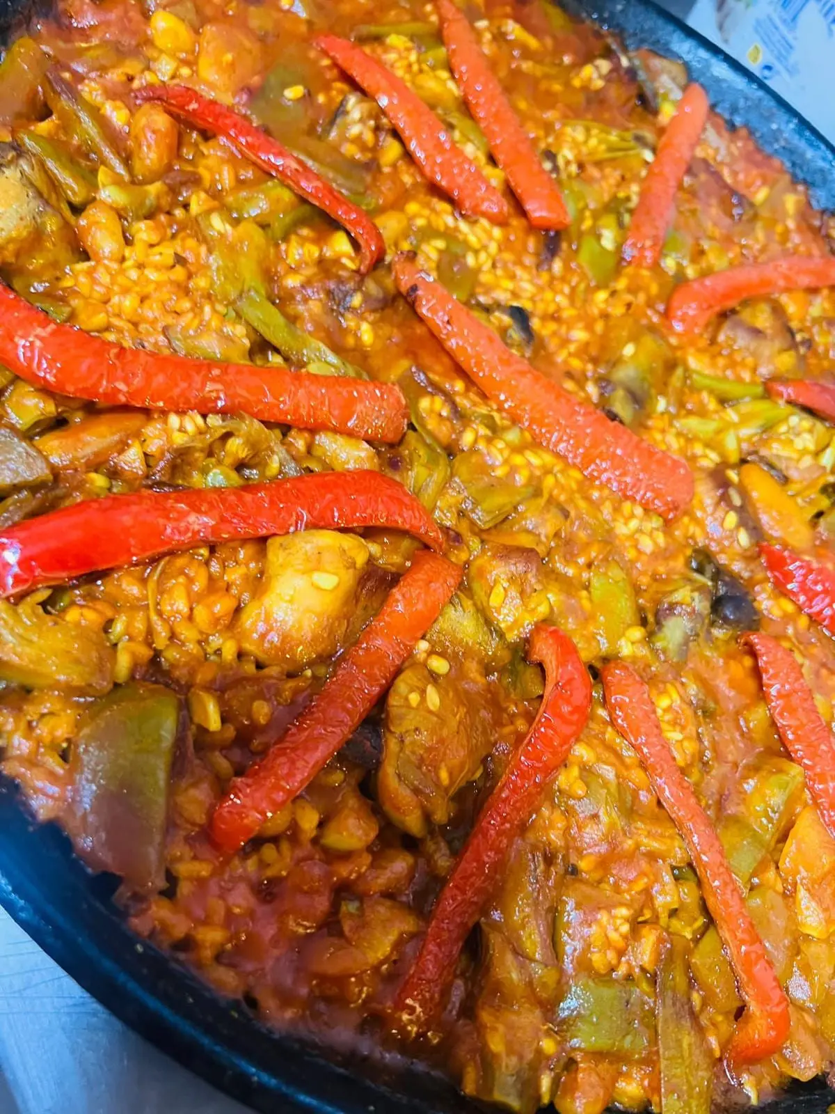 Arroz de verduras en la paella: judía verde, alcachofa, garrofón y tiras de pimiento rojo asado sobre el arroz.